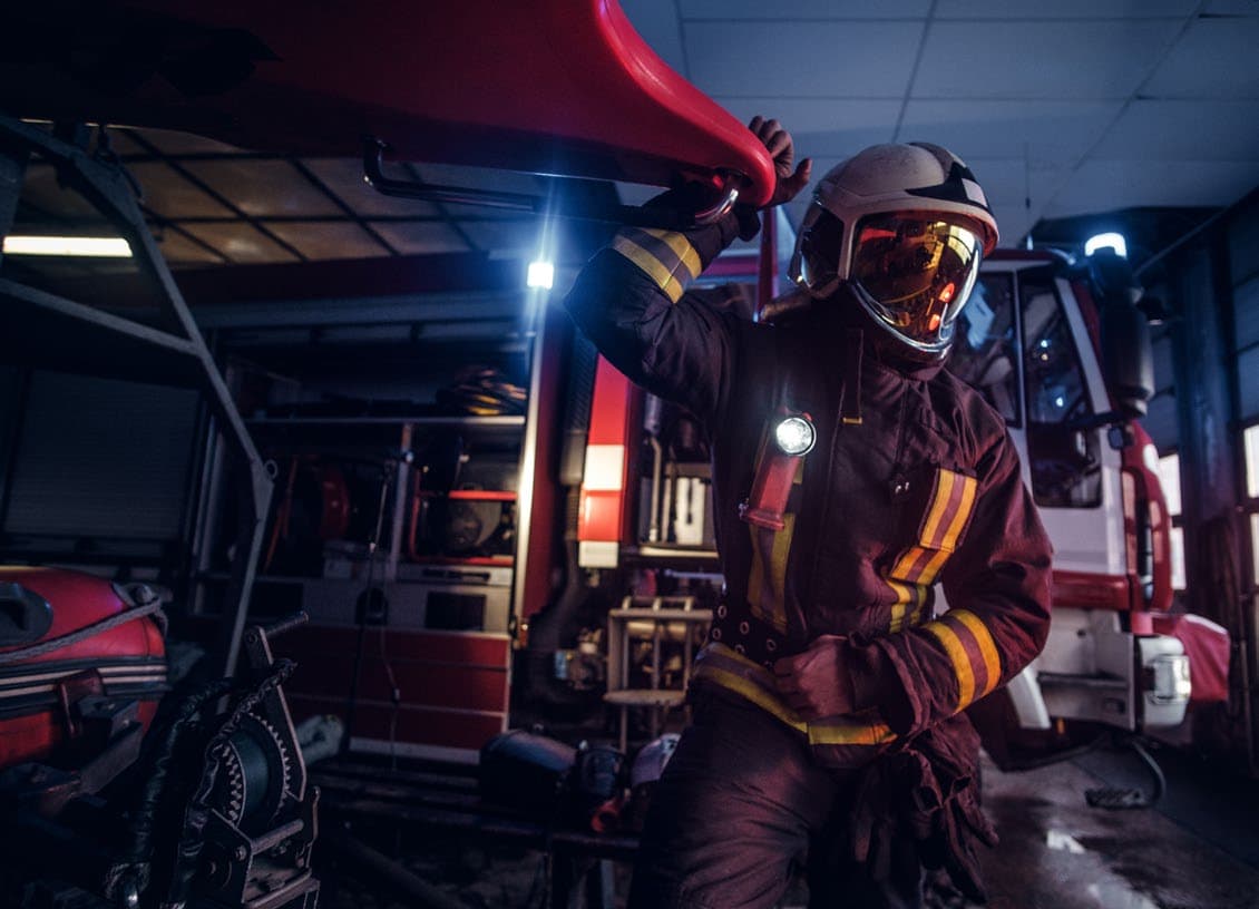 Firefighter in full protective gear beside a fire truck